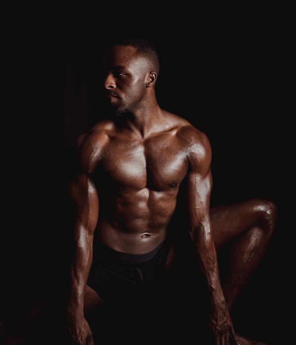 Man performing a powerful and controlled bodyweight exercise in a dark room.